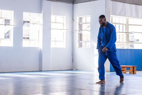Martial Artist Training in Sunlit Dojo with Blue Gi
