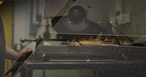 Machinist cutting steel with abrasive cut-off saw producing sparks at workshop bench