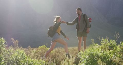 Caucasian couple hiking through picturesque mountain field