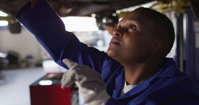 Image of african american female car mechanic checking car. working in car repair shop and running small feminine business concept.