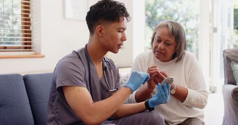 Physiotherapist Guiding Senior Woman during Hand Exercises at Home
