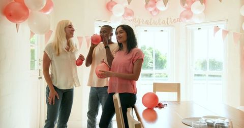 Diverse friends decorating for party celebration at home