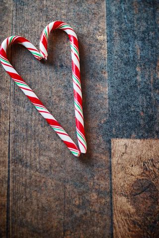 Heart made of christmas candy canes on wooden table