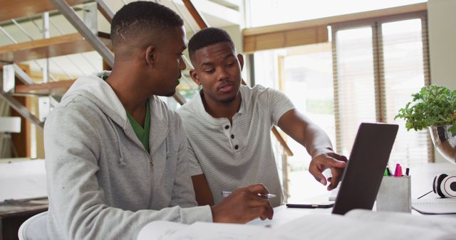 Two african american teenage twin brothers using a laptop and talking - Download Free Stock Photos Pikwizard.com