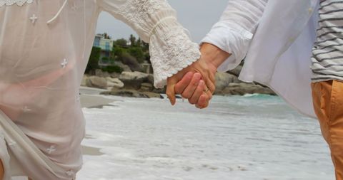 Romantic couple walking hand in hand along beach