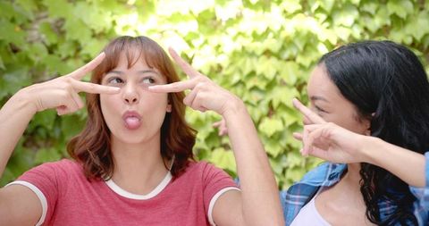 Joyful Biracial Friends Making Playful Gestures Outdoors