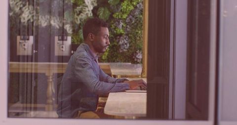 Focused man typing on laptop in modern urban workspace