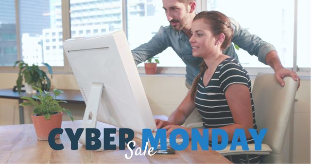 Coworkers collaborate at a computer in a modern office with large windows. It is Cyber Monday, indicated by text in the foreground. This image portrays teamwork and online shopping dynamics. Useful for marketing materials related to Cyber Monday sales, office productivity, or online shopping promotions.