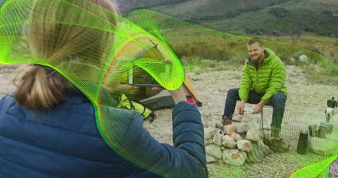 Man roasting marshmallows at campsite with absrtact design and copy space