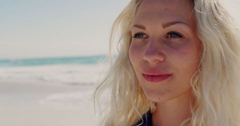 Blonde Woman Standing on Beach Enjoying Sunny Day