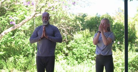 Couple practicing mindfulness meditation on porch overlooking lush garden with smartwatch