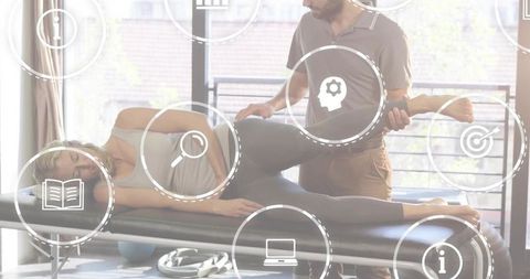 Therapist assisting woman with hip mobilization on treatment table in bright clinic