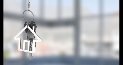 Silver house keychain in modern glass room with diffused light