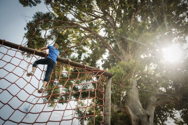 Woman climbing a net during obstacle course in boot camp