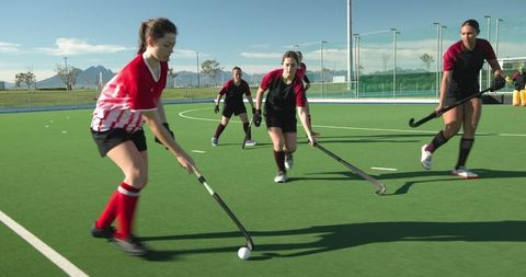 Female Athletes Playing Intense Field Hockey Match on Sunlit Field