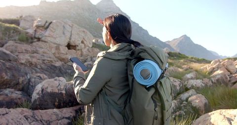 Exploring mountain landscape with backpack and smartphone