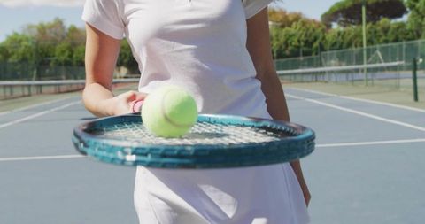 Balancing tennis player spinning ball on racquet on outdoor court