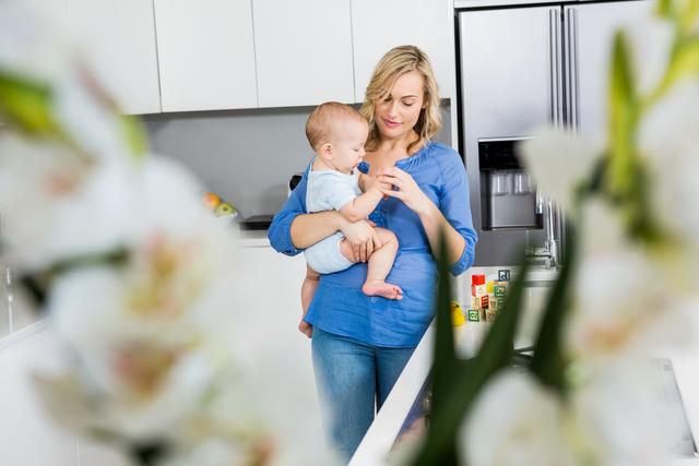 Mother holding her baby boy in kitchen at home
