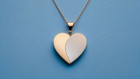 Elegant two-tone heart pendant on chain on light blue backdrop