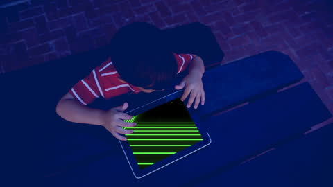 Boy Engaging with Tablet Game in Low Light