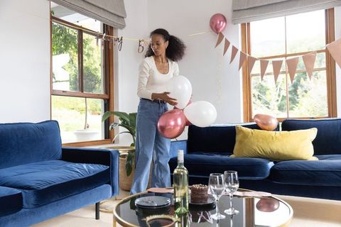 African american woman decorating living room with balloons for intimate home celebration