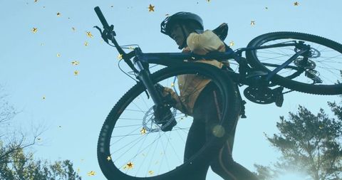 Cyclist Lifting Bike on Scenic Trail with Bright Sky