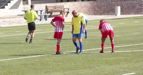 Soccer Referee Assisting Injured Player During Match