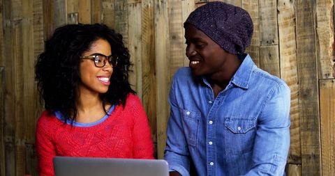 Happy Couple Enjoying Laptop Time in Rustic Cafe Setting