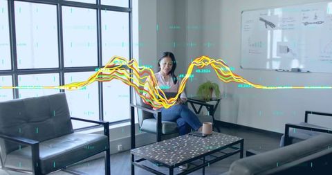 Asian Woman Analyzing Trends on Laptop in Modern Meeting Room