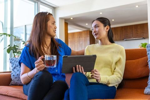 Mother Daughter Bonding with Tea and Tablet in Modern Living Room