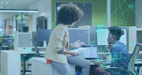 Women collaborating in modern office with laptop and digital network overlay