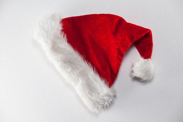 Santa hat with white fur trim lying on white background. Ideal for holiday promotions, Christmas-themed designs, greeting cards, festive advertisements, or seasonal blog posts.
