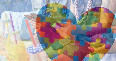 Friends exploring smartphones with autism awareness puzzle heart overlay