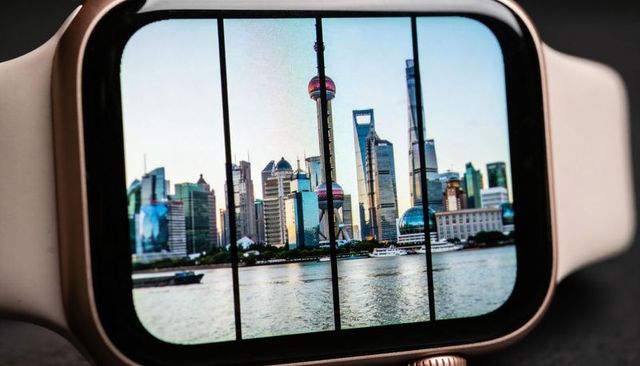 Rose-gold smartwatch displaying shanghai pudong skyline on screen with river reflection