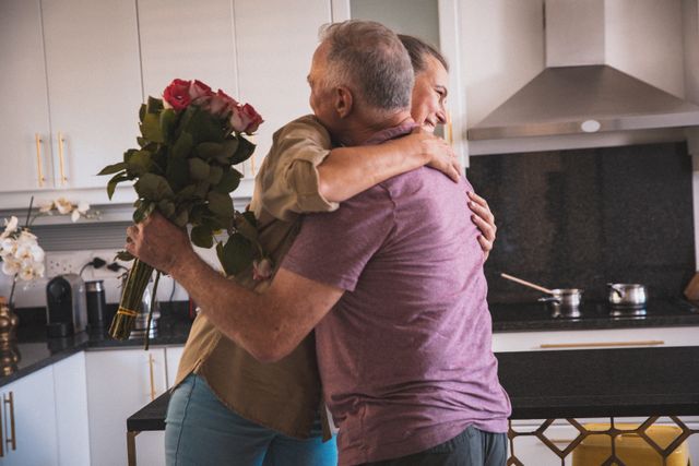 Senior Couple Embracing in Kitchen with Rose Bouquet - Download Free Stock Photos Pikwizard.com