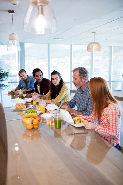 Group of colleagues having a casual lunch meeting in a modern office setting. Ideal for illustrating teamwork, corporate culture, and collaborative work environments. Useful for business blogs, corporate websites, and promotional materials highlighting a positive work atmosphere.