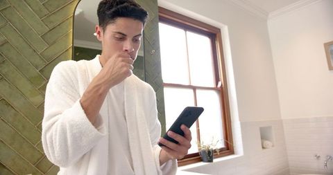 Man Multitasking: Brushing Teeth While Using Smartphone