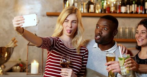Diverse Friends Taking Playful Selfie in Trendy Bar