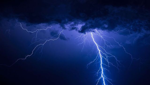 Dramatic Lightning Bolt Illuminates Night Sky with Vivid Blue Glow