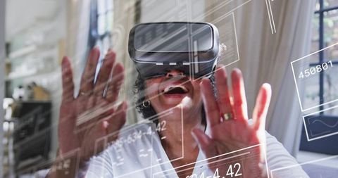 Senior woman wearing vr headset reaching toward floating ar interface in sunlit home