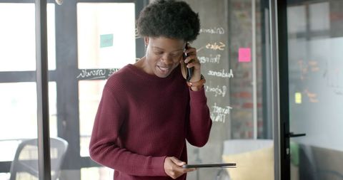 Casual Businessman Using Tablet and Talking on Phone at Home Office