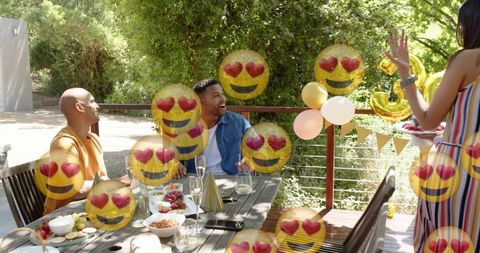 Friends laughing at backyard celebration with heart-eyes emoji overlays, balloons, champagne