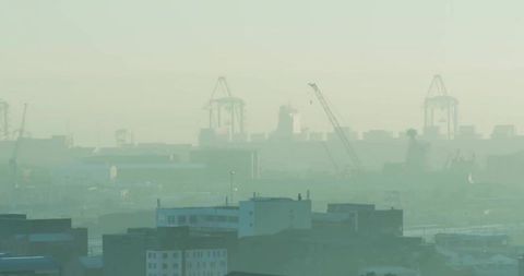 Container Cranes Over Port City Skyline in Hazy Smog