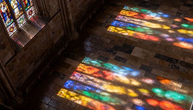 Stained glass light casting colorful bands across cathedral flagstone floor