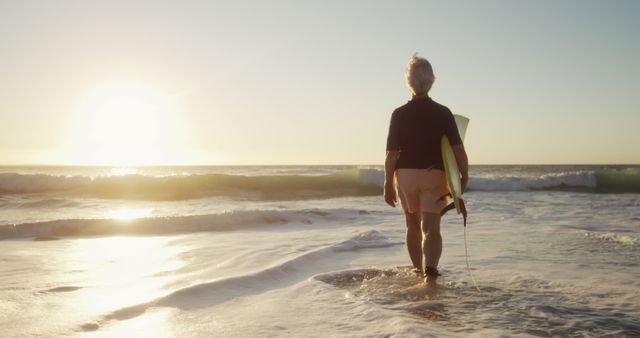 Older man with surfboard walking into ocean at sunrise - Download Free Stock Images Pikwizard.com