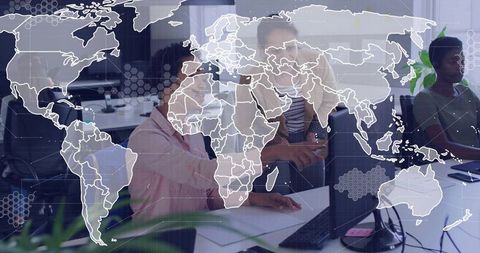 Diverse team collaborating over laptop with global network overlay in modern office