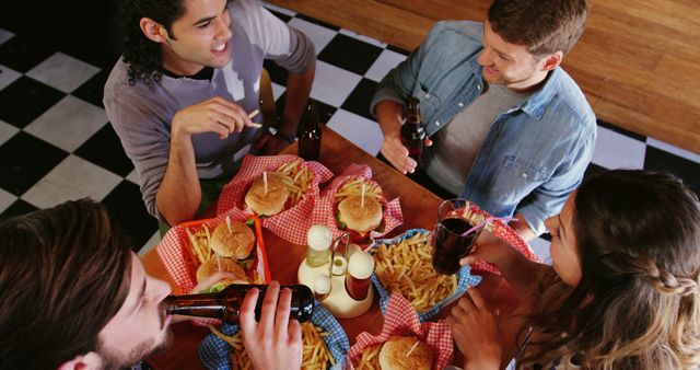 Friends Enjoying Burgers and Beers at Restaurant - Download Free Stock Images Pikwizard.com