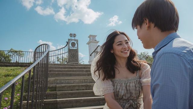 Young couple sharing romantic moment on sunlit stone stairs by ornate garden gate