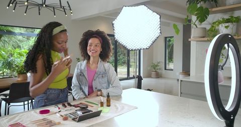 Filming makeup tutorial on kitchen island with ring light and softbox, diverse creators collaboratin