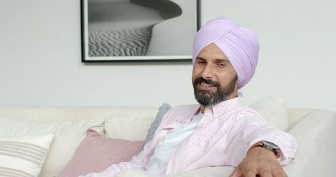 Smiling Man in Turban Relaxing on Cozy Couch at Home